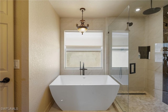 bathroom featuring a freestanding tub, a shower stall, a sink, and a textured wall