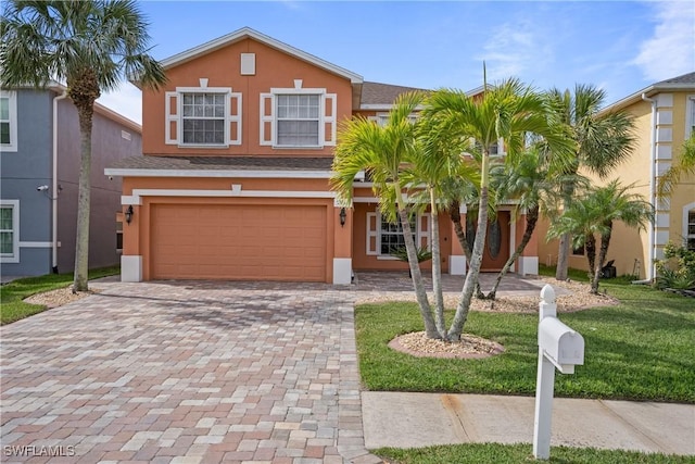 view of front of house with a garage, decorative driveway, a front lawn, and stucco siding