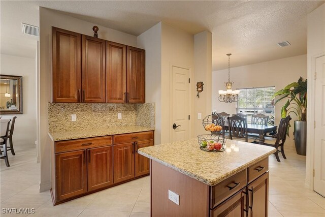 kitchen featuring brown cabinets, a kitchen island, visible vents, and pendant lighting