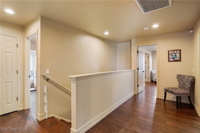 hallway featuring recessed lighting, dark wood-type flooring, an upstairs landing, visible vents, and baseboards