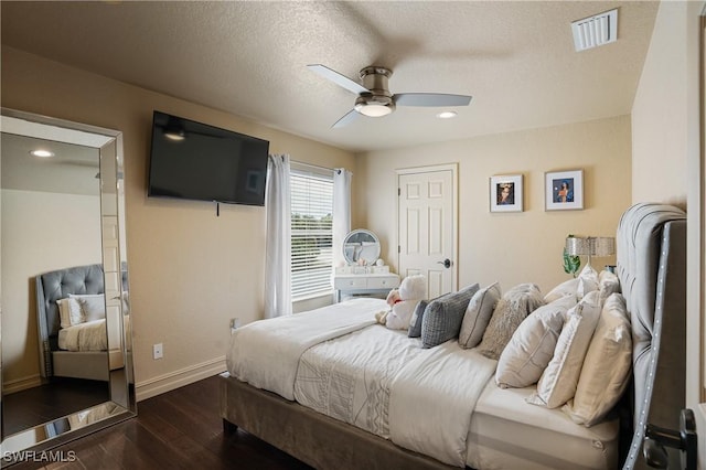 bedroom with a textured ceiling, ceiling fan, dark wood-type flooring, visible vents, and baseboards