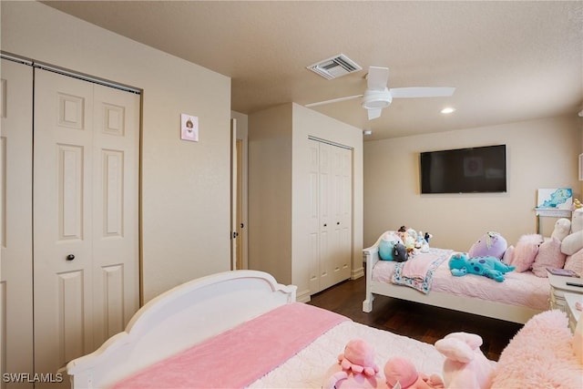 bedroom with visible vents, a ceiling fan, dark wood-style floors, multiple closets, and recessed lighting