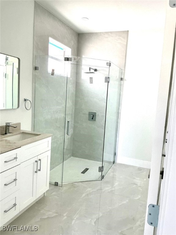 full bathroom featuring marble finish floor, vanity, and a shower stall