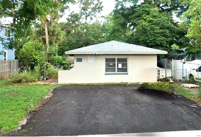 view of home's exterior featuring a shingled roof, fence, and stucco siding