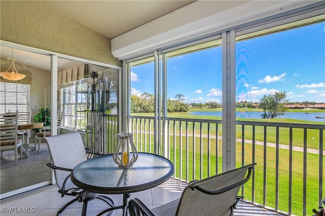 sunroom featuring a water view and lofted ceiling