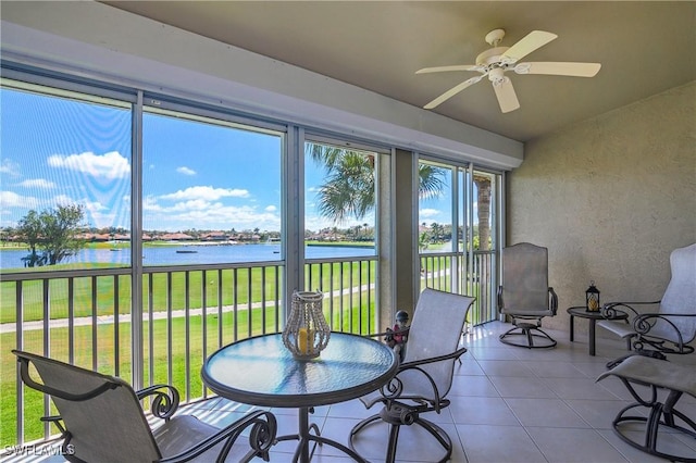 sunroom featuring ceiling fan and a water view