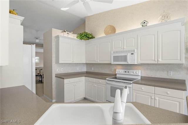 kitchen featuring white appliances, white cabinets, lofted ceiling, ceiling fan, and a sink