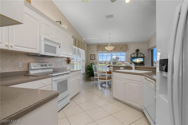 kitchen with white appliances, hanging light fixtures, white cabinetry, a sink, and light tile patterned flooring