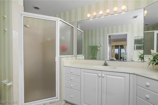 ensuite bathroom with visible vents, connected bathroom, a shower stall, vanity, and wallpapered walls