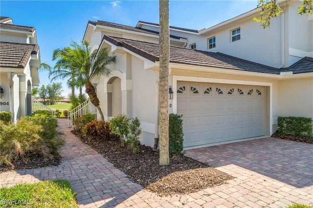 view of side of home with decorative driveway and stucco siding