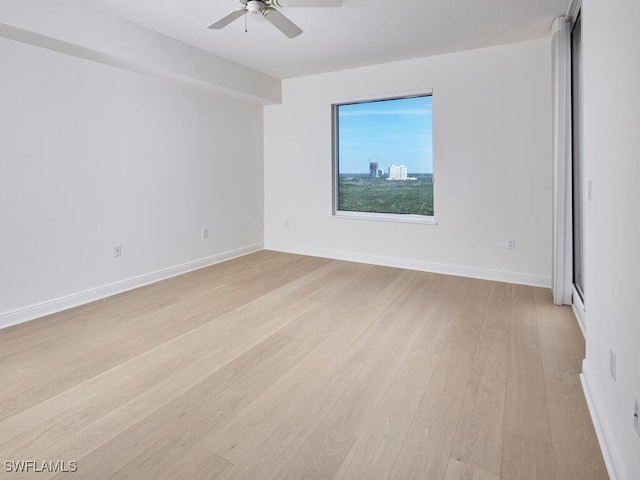 spare room featuring light wood-style floors, baseboards, and a ceiling fan