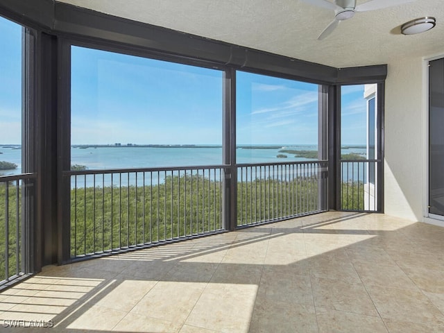 unfurnished sunroom with a water view, plenty of natural light, and ceiling fan