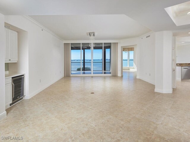 unfurnished living room featuring wine cooler, crown molding, visible vents, bar area, and baseboards