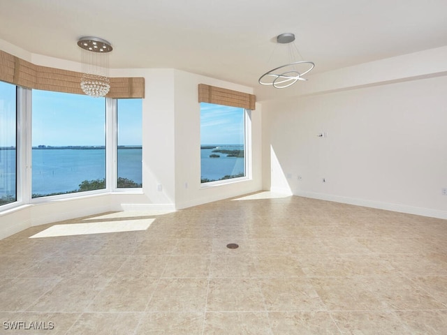 spare room featuring plenty of natural light, a water view, baseboards, and a notable chandelier