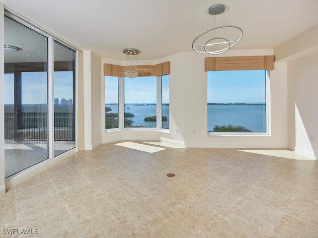 unfurnished room featuring a water view and baseboards