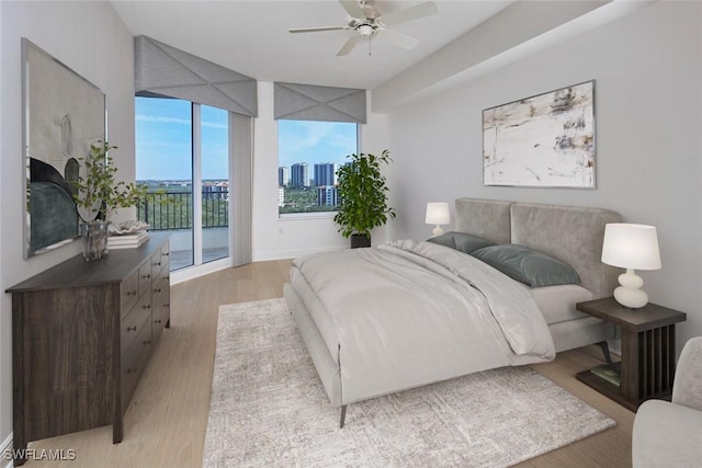 bedroom with baseboards, a ceiling fan, access to outside, a view of city, and light wood-style floors