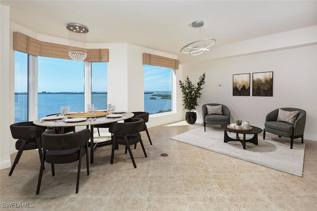 dining room with a chandelier, a water view, and baseboards