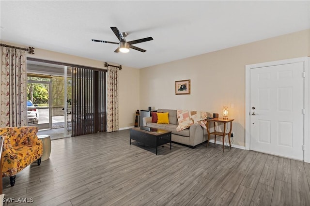 living area with wood finished floors, a ceiling fan, and baseboards