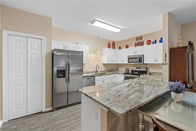 kitchen featuring appliances with stainless steel finishes, white cabinetry, and a peninsula