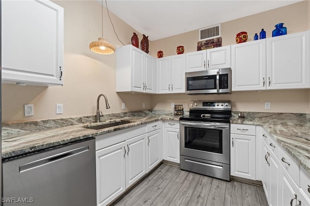 kitchen featuring stainless steel appliances, pendant lighting, white cabinets, and a sink