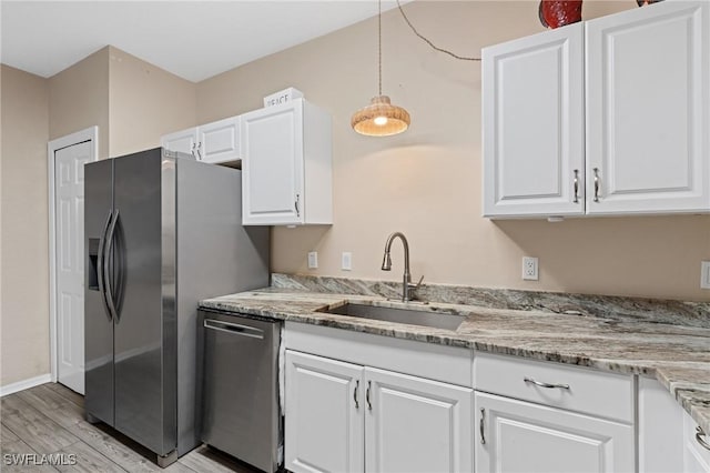 kitchen with appliances with stainless steel finishes, a sink, white cabinetry, and pendant lighting