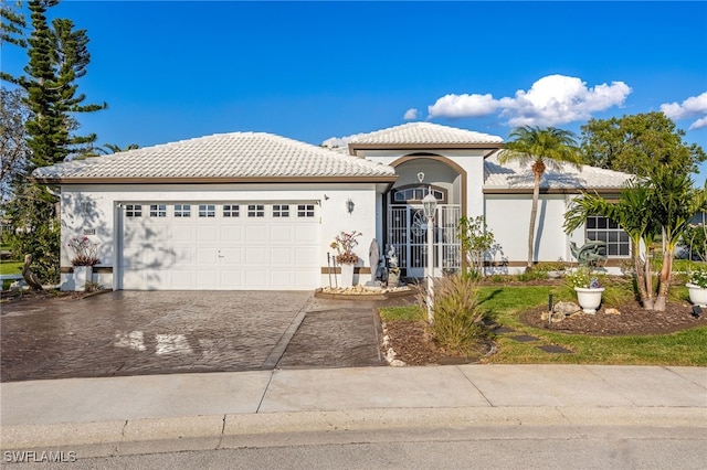 view of front of property featuring decorative driveway, a tile roof, an attached garage, and stucco siding