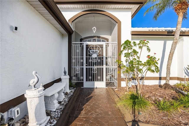 view of exterior entry featuring a gate and stucco siding