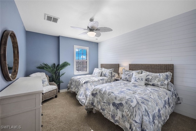 bedroom featuring wood walls, ceiling fan, visible vents, and carpet flooring