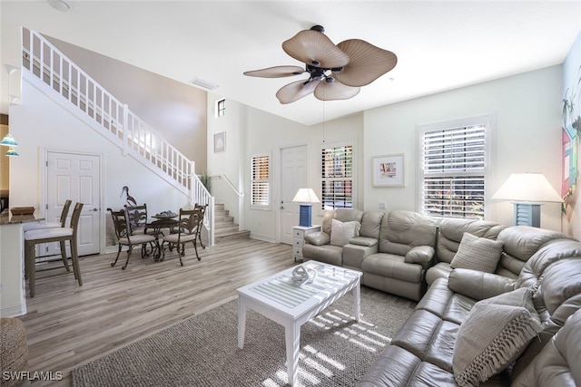 living area featuring stairs, ceiling fan, visible vents, and light wood-style floors