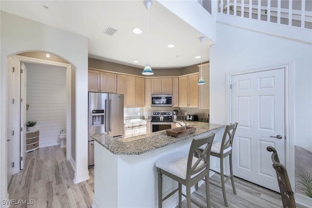 kitchen with visible vents, light wood-style flooring, appliances with stainless steel finishes, light brown cabinets, and a peninsula