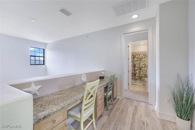 office space with built in desk, light wood-type flooring, visible vents, and baseboards