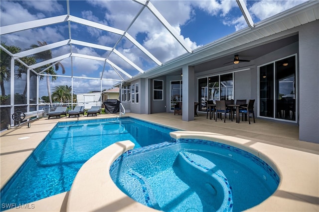 view of swimming pool with glass enclosure, ceiling fan, a grill, a patio area, and a pool with connected hot tub