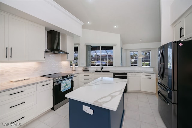 kitchen featuring a kitchen island, freestanding refrigerator, stainless steel range with electric cooktop, wall chimney range hood, and a sink