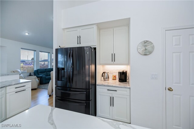 kitchen featuring decorative backsplash, light wood-style floors, open floor plan, white cabinets, and black fridge