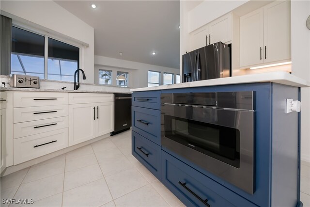 kitchen with light tile patterned floors, recessed lighting, white cabinetry, a sink, and refrigerator with ice dispenser