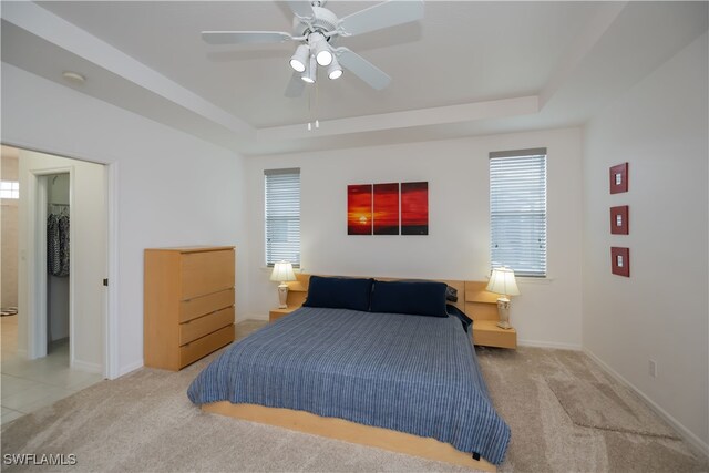 bedroom with carpet floors, baseboards, and a tray ceiling