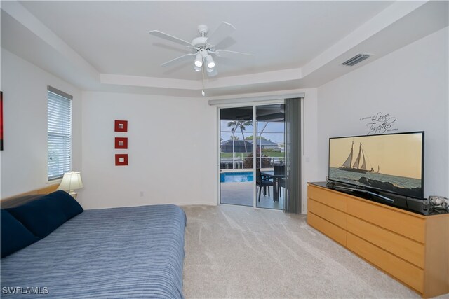 bedroom with access to exterior, visible vents, multiple windows, and a tray ceiling