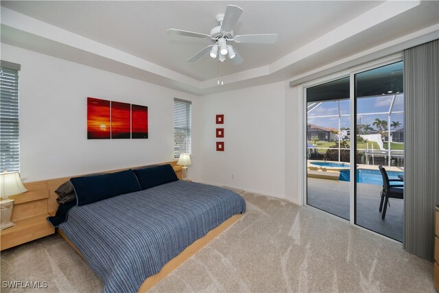 carpeted bedroom with ceiling fan, a tray ceiling, and access to exterior