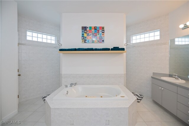 full bathroom with a jetted tub, tile patterned flooring, vanity, and tile walls