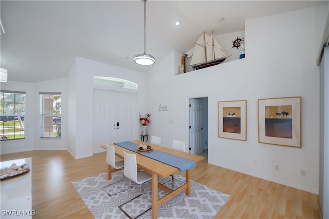 dining room with high vaulted ceiling, baseboards, and light wood finished floors