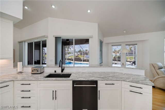 kitchen featuring light stone countertops, white cabinets, a sink, and recessed lighting