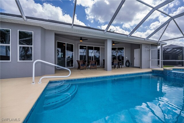 view of swimming pool with a patio area, a pool with connected hot tub, glass enclosure, and a ceiling fan