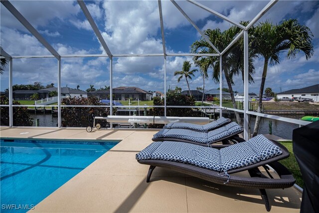 pool featuring glass enclosure, a patio, and a water view