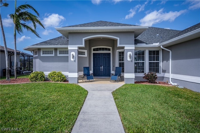 doorway to property featuring roof with shingles, a lawn, and stucco siding