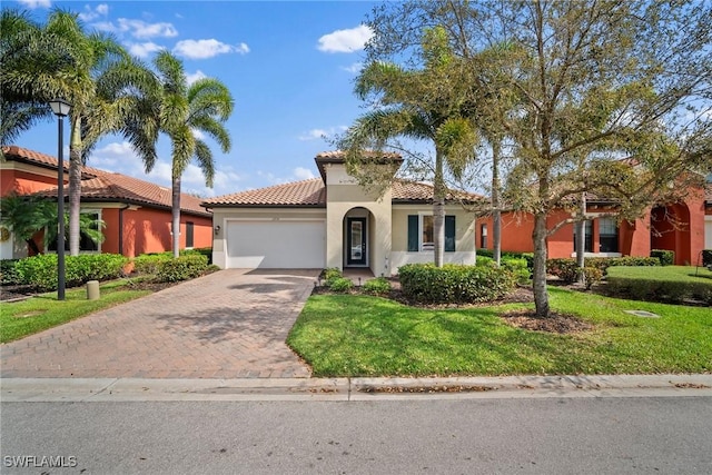 mediterranean / spanish-style home with a garage, a tiled roof, decorative driveway, a front lawn, and stucco siding