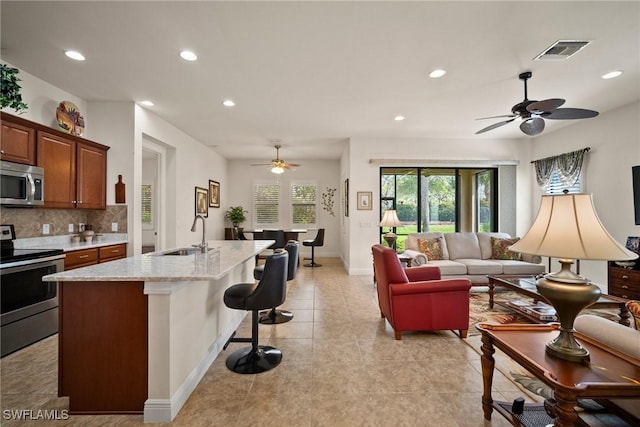 kitchen featuring stainless steel appliances, a sink, visible vents, a kitchen breakfast bar, and open floor plan