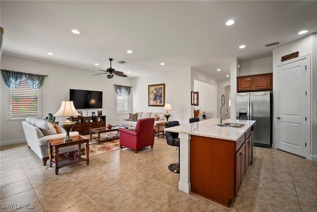 kitchen featuring a center island with sink, visible vents, open floor plan, stainless steel refrigerator with ice dispenser, and a sink