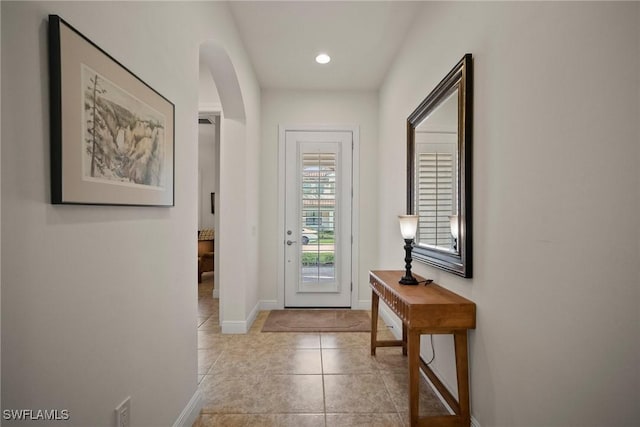 entryway featuring arched walkways, recessed lighting, baseboards, and light tile patterned floors