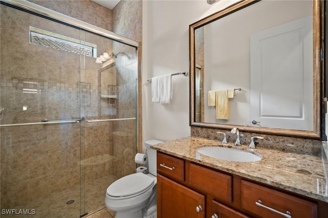 bathroom with a stall shower, vanity, and toilet