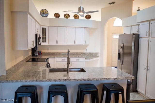 kitchen with a peninsula, a breakfast bar, a sink, visible vents, and white cabinetry